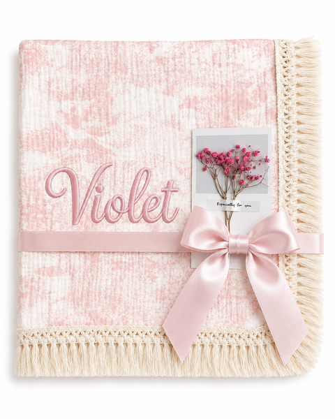 Blush Naturel pink patterned muslin blanket with Violet embroidered in pink, cream fringed edging and pale pink ribbon.
