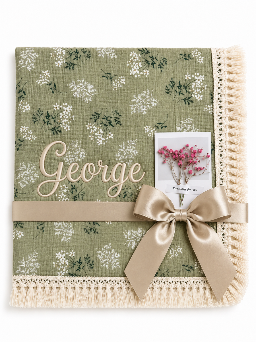 Botanica green floral muslin baby blanket with George embroidered in cream, fringed edging and champagne ribbon.