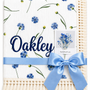 Cornflower Meadow muslin baby blanket with blue flowers, Oakley embroidered in navy, cream fringe and blue ribbon.