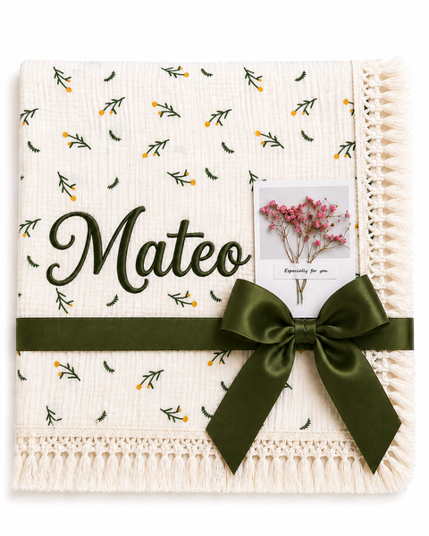 Cream Dandelions muslin blanket with delicate green and yellow botanical print, Mateo name embroidery and dark-green ribbon.