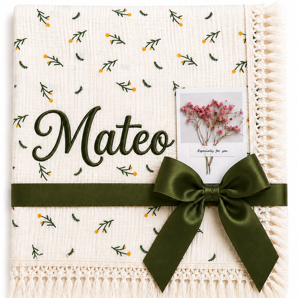 Cream Dandelions muslin blanket with delicate green and yellow botanical print, Mateo name embroidery and dark-green ribbon.