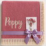 Dusty Pink muslin baby blanket personalised with Poppy in cream embroidery, a fringed border and lilac ribbon.