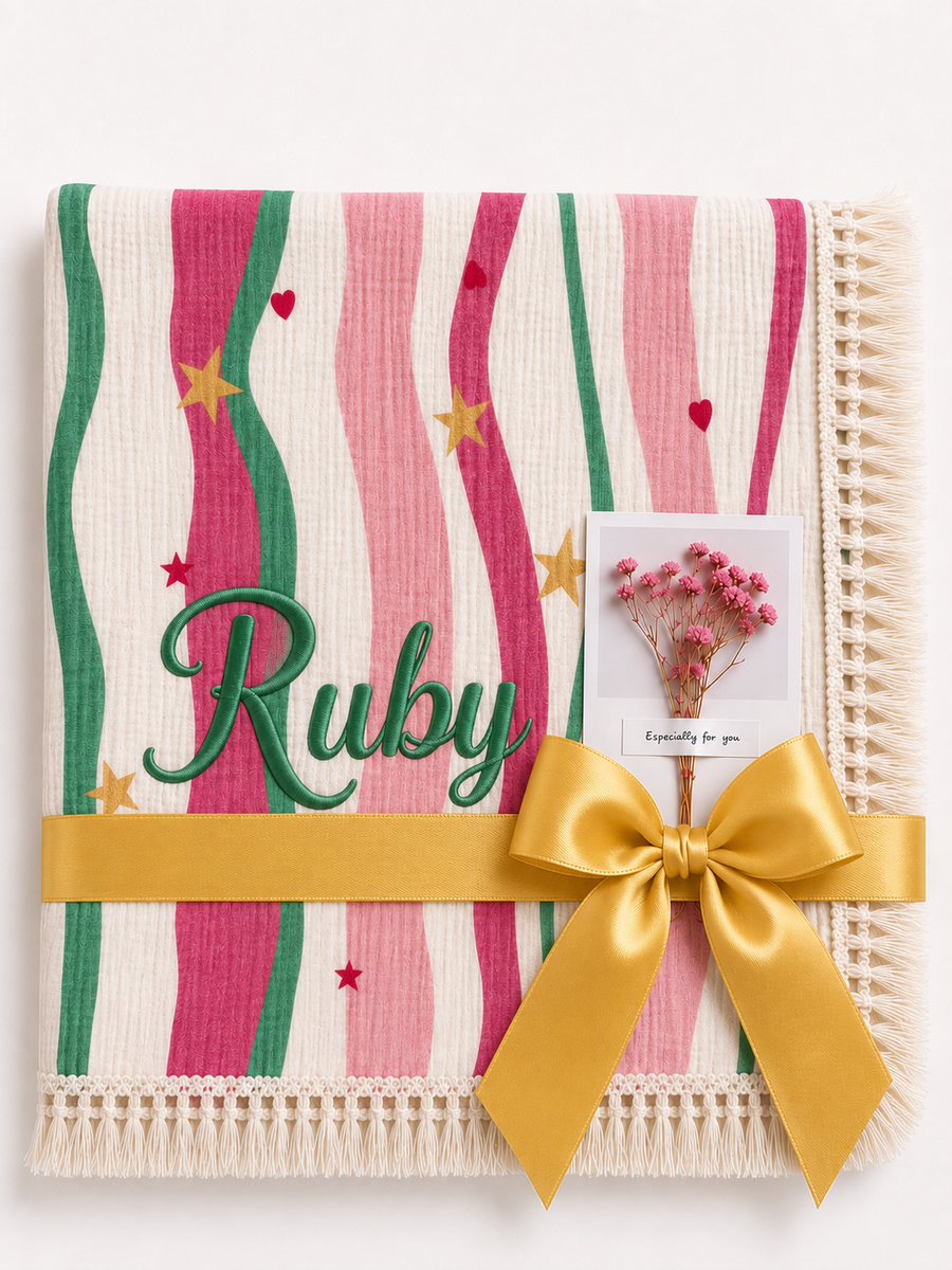 Summer Waves muslin blanket with pink and green wavy stripes, Ruby embroidered in green, cream fringe and yellow ribbon.