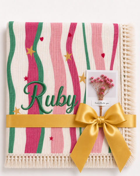Summer Waves muslin blanket with pink and green wavy stripes, Ruby embroidered in green, cream fringe and yellow ribbon.