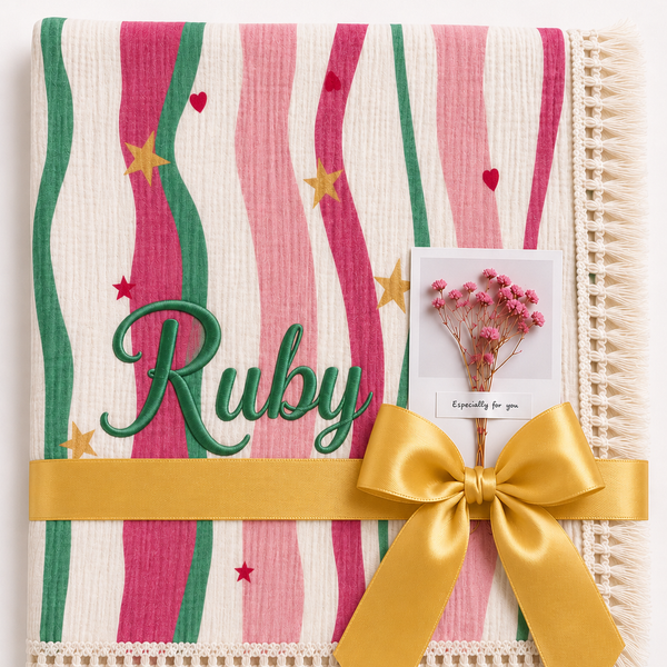 Summer Waves muslin blanket with pink and green wavy stripes, Ruby embroidered in green, cream fringe and yellow ribbon.