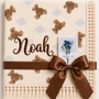 Cream teddy-print muslin baby blanket personalised with Noah embroidered in brown, with a fringed border.