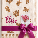 Cream Twin Bear muslin baby blanket with teddy-face print, Elsie embroidered in pink and a magenta ribbon.